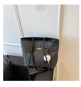 Détail du sac cabas tissé avec lanières en cuir et breloque boule en peluche blanche
