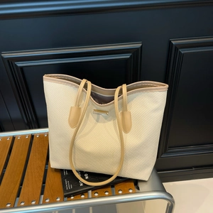 Grand sac cabas tressé avec bordure en cuir marron posé sur un banc en bois chic