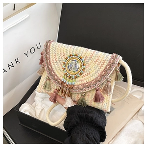 Dettaglio borsa di paglia boho con perline etniche e nappe multicolore