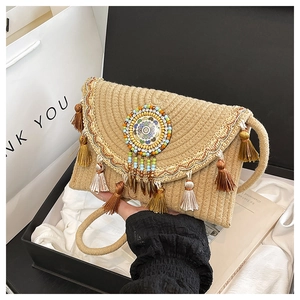Dettaglio borsa in paglia intrecciata con frange boho e ornamento mandala di perline