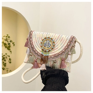 Dettaglio ravvicinato della borsa in paglia intrecciata con frange colorate e perline