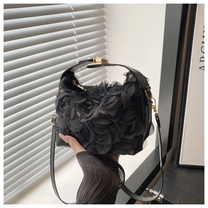 Detail of black shell bag featuring 3D mesh petals and gold metal clasp closure