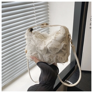 Close-up of white lace rose handbag held by hand featuring elegant texture and gold hardware