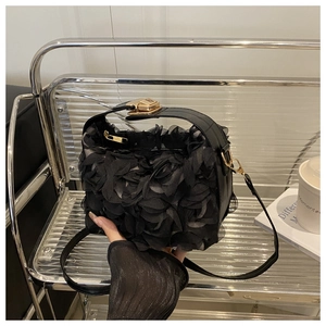 Gros plan d'un sac de soirée noir avec fleurs en dentelle 3D et fermoir doré chic
