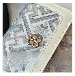 Detail of floral jacquard fabric with gold clover buckle and cream leather trim