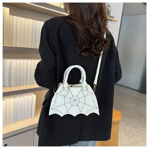 Detail view of white bat-wing handbag with black embroidered spider web stitching