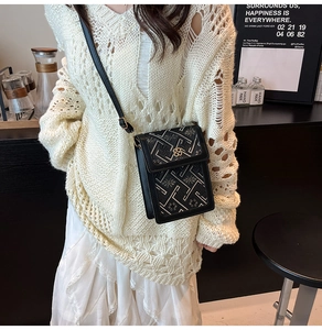Close-up of black crossbody phone bag with white geometric embroidery and gold hardware