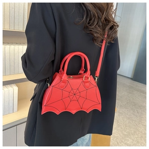 Detail of red bat-shaped handbag with spider web stitching and gold metal hardware