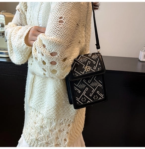 Detail of a chic bucket bag with black and white floral pattern and silver floral clasp