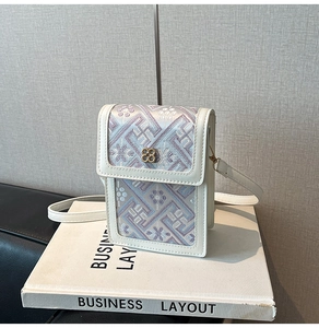 Detail of embroidered floral crossbody phone bag with a gold flower lock and white leather trim