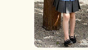 Gros plan d'une jupe plissée grise et de chaussures Mary Jane noires pour fille en plein air