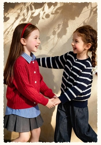 Détails de maille d'un gilet rouge torsadé et d'un pull rayé pour petite fille
