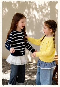 Détail de gilets tricotés pour filles avec motifs torsadés et design rayé à boutons