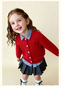 Close-up of red cable knit girls cardigan with white buttons and stripe shirt collar