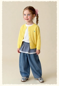 Detail of yellow knit cardigan with blue 'a' embroidery and white tee for girls