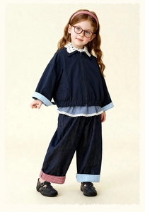 Detail van blauw meisjesjack met kantkraag en asymmetrische geruite omslagen op jeans