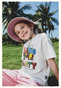 Detalle de camiseta infantil con estampado de dibujos y conjunto rosa de verano