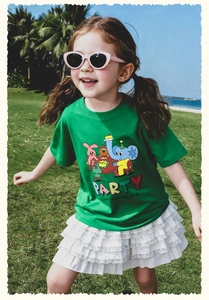 Detalle de camiseta verde de fiesta y conjunto de falda de encaje blanco para niña