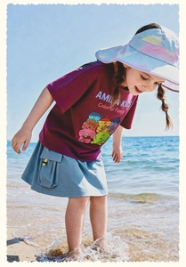 Detalle de camiseta morada de dibujos y falda cargo para niñas en actividades de playa