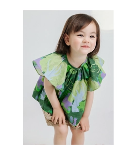 Detail of floral girl's shirt with ruffled sleeves and beige casual cotton shorts