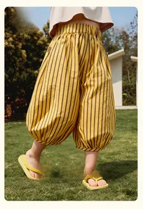Gros plan du pantalon bouffant à rayures jaunes et brunes pour enfant sur de l'herbe