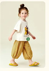 Détail d'une tenue d'été pour enfants avec t-shirt blanc à dessin et pantalon rayé jaune