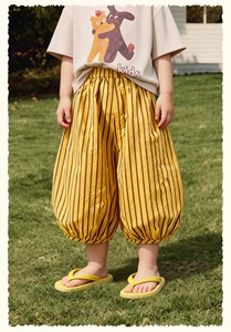Photo en extérieur d'un pantalon d'été rayé jaune pour enfant à jambes larges avec t-shirt