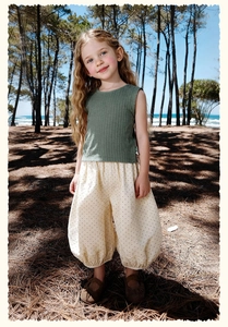 Détail d'un haut sans manches vert et d'un pantalon bouffant à pois pour enfant