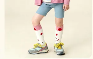 Gros plan de chaussettes hautes blanches pour filles à pois rouges et revers roses