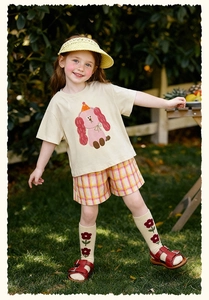 Détail d'une tenue d'été pour fille avec t-shirt chiot rose et short à carreaux jaunes