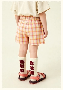 Vue arrière d'une fille en t-shirt beige et short à carreaux rose et jaune
