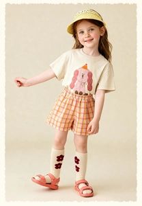 Fille portant un short à carreaux jaune avec t-shirt beige chien de dessin animé et chapeau