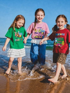 Tres niños en la playa con camisetas de algodón con dibujos animados y conjuntos de verano