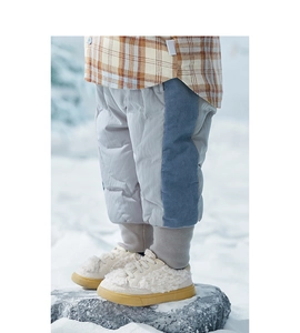 Detailopname van de warme corduroy broek en geblokt shirt voor kinderen in sneeuw