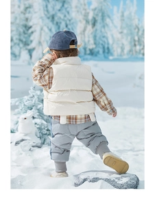 Detailoverzicht van kinderwinteroutfit met gewatteerd vest en corduroy broek in de sneeuw