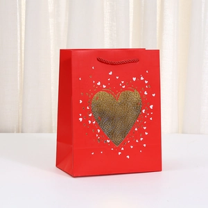 Rote Papiertragetasche mit goldenem Herzaufdruck und roten Kordelgriffen für Geschenke