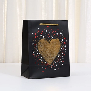 Schwarze Geschenktüte aus Kraftpapier mit goldenem Herzglitzer und Webgriffen