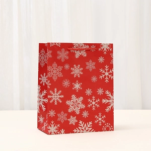 Festive red Christmas gift paper bag with white snowflake patterns and woven handles