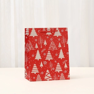 Detail of red Christmas gift bag with white snowflake and tree patterns and red rope handles