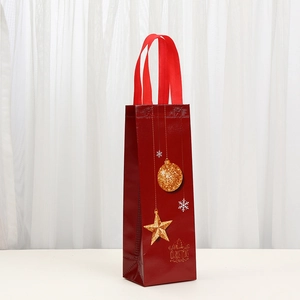 Detail of red non-woven Christmas wine bag with gold ornaments and Merry Christmas print