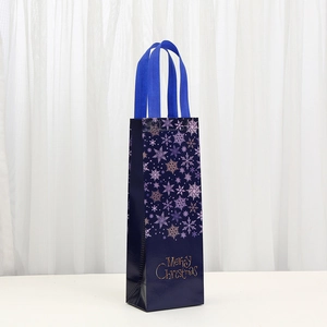 Blue non-woven Christmas wine bag with golden Merry Christmas text and snowflake prints
