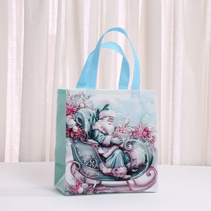 Christmas non-woven gift bag with blue Santa Claus illustration on a white surface
