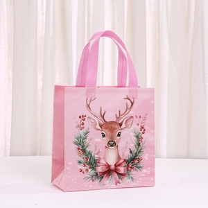 Detailed view of pink non-woven Christmas gift bag with cartoon reindeer and wreath