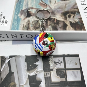 Mini-Fußball-Schlüsselanhänger mit Weltflaggen auf weißem Buchhintergrund für Fans