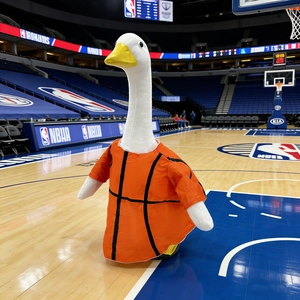 Funny white goose plush toy wearing orange basketball jersey in sports arena