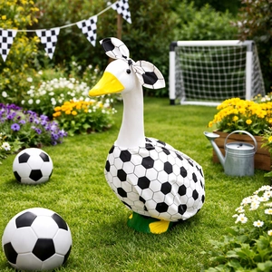 Detailed outdoor view of a soccer-themed garden goose statue with a bow on a lawn