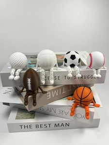 Macro shot of 3D-printed sports ball action figures on books with movable joints