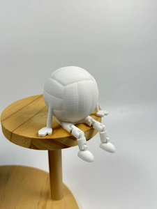Detail view of 3D printed articulated robot figure with volleyball head on wooden stand
