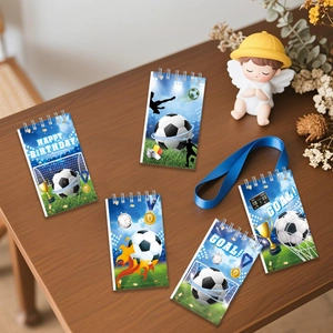 Five football-themed spiral notebooks with birthday trophies on a wooden desk