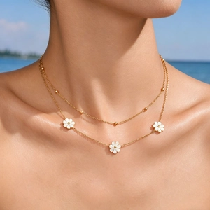 Gros plan d'un collier marguerite double couche doré sur modèle avec fond de plage